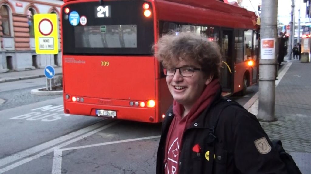 Kid smiling at camera with bus behind him